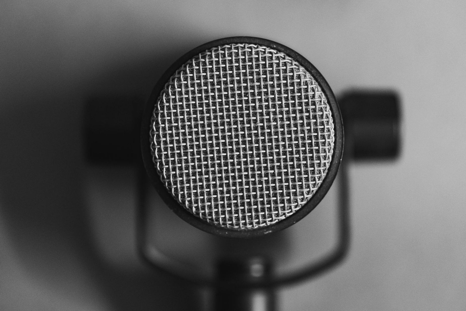 Lähikuva studiomikrofonin pyöreästä metalliverkosta mustavalkoisena